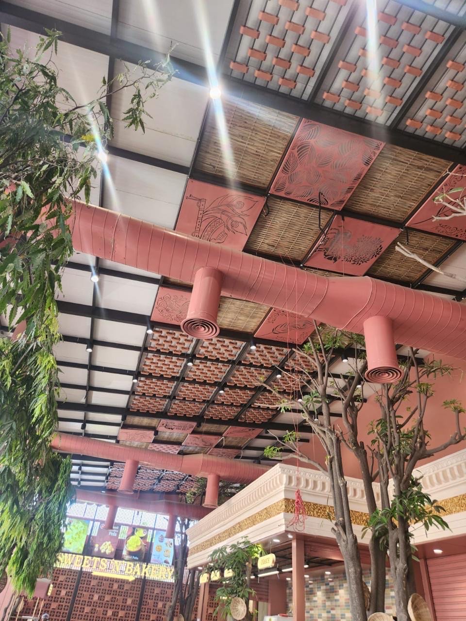 Bamboo blind panels between terracotta lattice across a café ceiling in Mysore